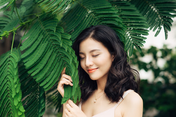 Portrait of pretty young woman standing near leaves outdoors