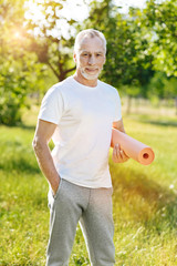 Wall Mural - Positive aged man holding roll mat for yoga