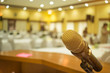 © smolaw11 - Microphone on podium with abstract blurred of conference hall or seminar room event background