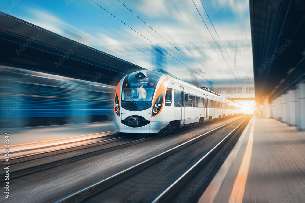 High speed train at the railway station at sunset in Europe. Modern intercity train on railway platform. Urban scene with beautiful passenger train on railroad and buildings. Railway landscape - obrazy, fototapety, plakaty 