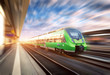 High speed train in motion at the railway station at sunset in Europe. Beautiful green modern train on the railway platform with motion blur effect. Industrial scene with passenger train on railroad