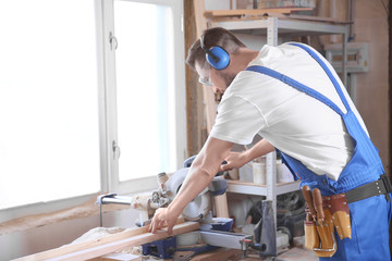 Sticker - Focused carpenter sawing timber strip in workshop