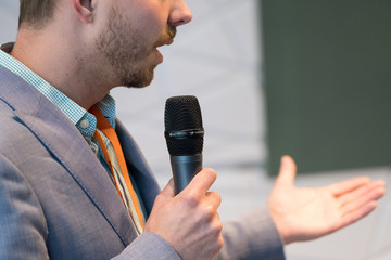 Speaker at conference holding microphone in the hand