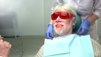 Wall Mural - Dentists with elderly patient. Man in dental chair smiling. Cure diseases of teeth.