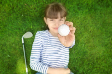 Canvas Print - Cute girl with ball and driver lying on golf course, closeup