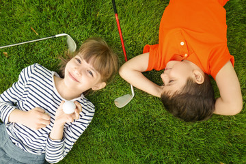 Poster - Cute children with ball and drivers lying on golf course