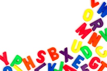 Wall Mural - Corner border of colorful toy magnetic alphabet letters over a white background