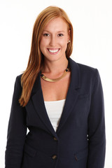 Smiling attractive businesswoman in a blue suit with white shirt standing against a white background smiling in red hair.