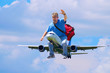 A happy man with a red duffel bag is waving as he flies through the air riding on an airplane like someone would ride a horse - happy frequent flyer flying traveler and travel agency concept.