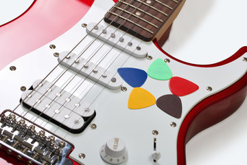 Five colored picks on a guitar on a white background