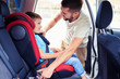 © ArtFamily - Small son in car seat being put in back of car by father