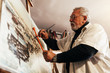© santypan - Old man artist painting oils in his studio.