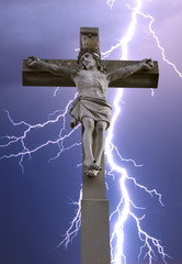 stone cross with Jesus and sky with lightning