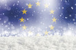 Defocused European union flag as a winter Christmas background with falling snow, snowdrift and bokeh