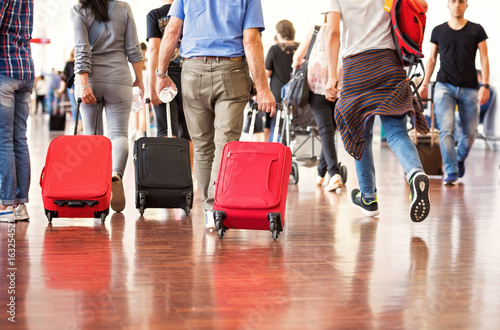 Plakat Podróżni z walizkami idącymi przez lotnisko