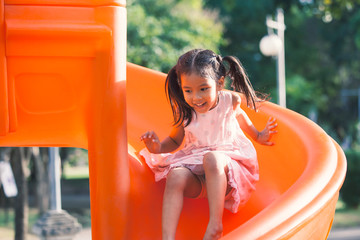 Wall Mural - Cute asian child girl having fun to play slider in the playground in summer time