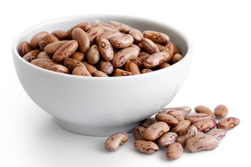 Wall Mural - Dry pinto beans in white ceramic bowl isolated on white. Spilled beans.