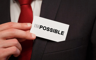 Poster - businessman putting a card with text impossible in the pocket