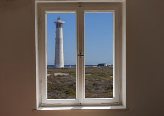 Closed window and a view of a lighthouse on a sunny day