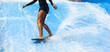 Girl on black swimsuit surfing on wave pool with small board in the island of Phuket, Thailand
