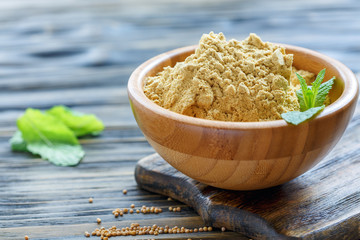 Wall Mural - Mustard powder in a wooden bowl.