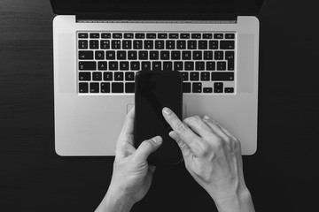 Poster - cyber security internet and networking concept.Businessman hand working mobile phone on laptop computer background,black and white