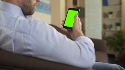 Confident male reading political news on smartphone with green screen, app