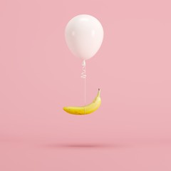 Wall Mural - Floating White balloon and banana on pink background. minimal fruit idea concept.