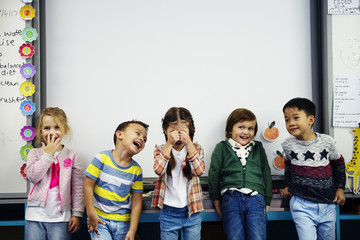 Wall Mural - Group of diverse kindergarten students standing together in classroom