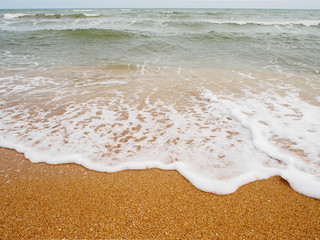 Wall Mural - Wide angle view of ocean waves with sea foam crashing into the orange colored sands of a beach. Chanthaburi, Thailand. Travel and nature concept.