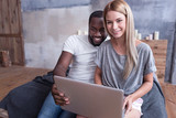 Fototapeta Tulipany - Smiling international couple making online purchase at home