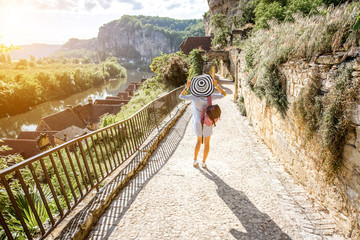 Wall Mural - Young woman tourist with backpack and hat walking on the narrow street with beautiful landscape view in the famous La Roque Gageac village in France