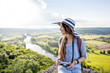 Young woman tourist in hat enjoying sunset view on the beautiful landscape with Dordogne river in France