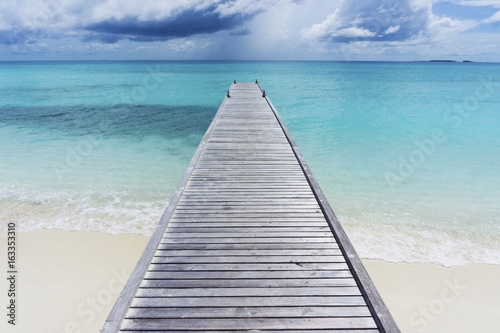 Wooden pier over tropical clear blue sea