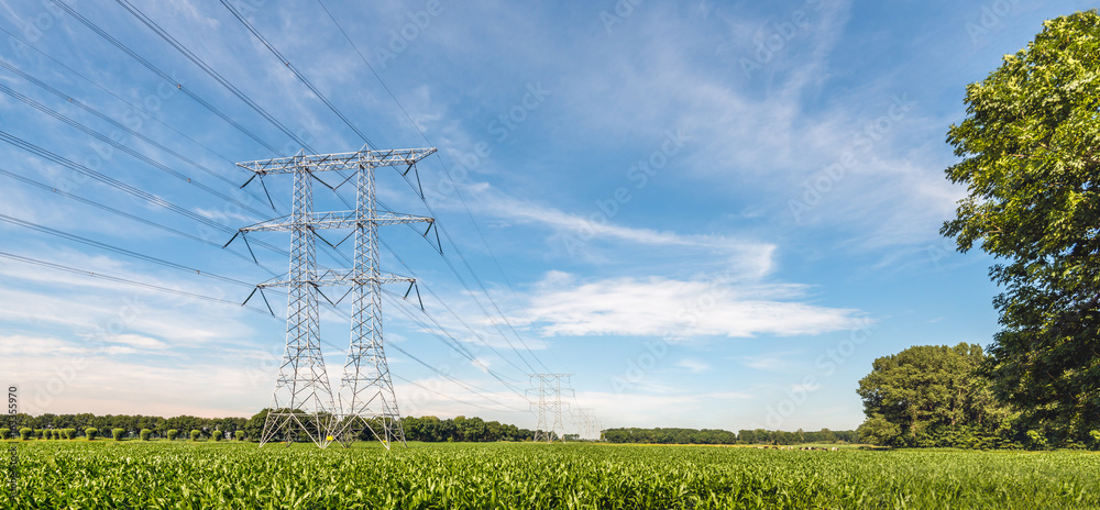 Electricity pylons and cables in an agricultural landscape with silage ...