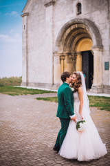 gorgeous wedding couple . The happinest brides embracing near castle. Groom and bride embrace on a background of the castle. very lucky in love wedding day. The groom holds the bride on hands