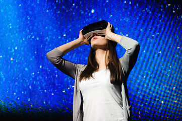 a beautiful girl wearing a virtual reality device, standing on the background of the sky