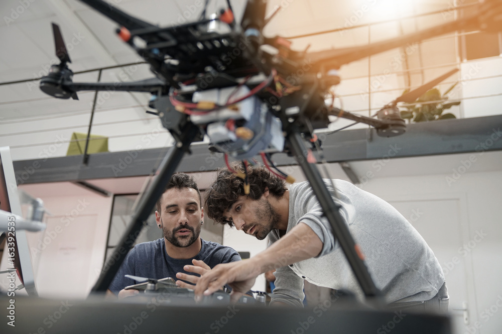 Engineer and technician working together on drone in office - obrazy, fototapety, plakaty 