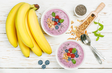 Wall Mural - Healthy delicious smoothie from banana and fresh berries raspberry and blueberry granola with Chia seeds and mint leaves in white bowl