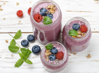 Wall Mural - Healthy delicious smoothie from banana and fresh berries raspberry and blueberry granola with Chia seeds and mint leaves in portion jars