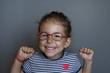 Happy little girl wearing red glasses against myopia. Development of mental abilities at an early age