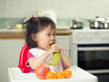 Baby Girl Eating  Fruit At Home