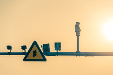 CCTV security camera and traffic sign on a pole against sky at twilight