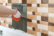 A tile's hand is holding a notched trowel.
