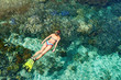 © soft_light - woman in swimsuit snorkeling in clear tropical sea above coral reef.