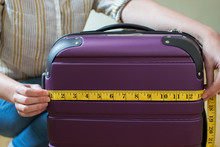 Close Up Of Woman Measuring Suitcase Before Holiday