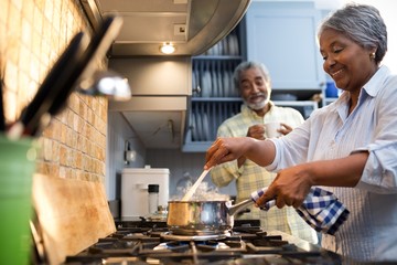 Wall Mural - Smiling couple preparing food in kitchen