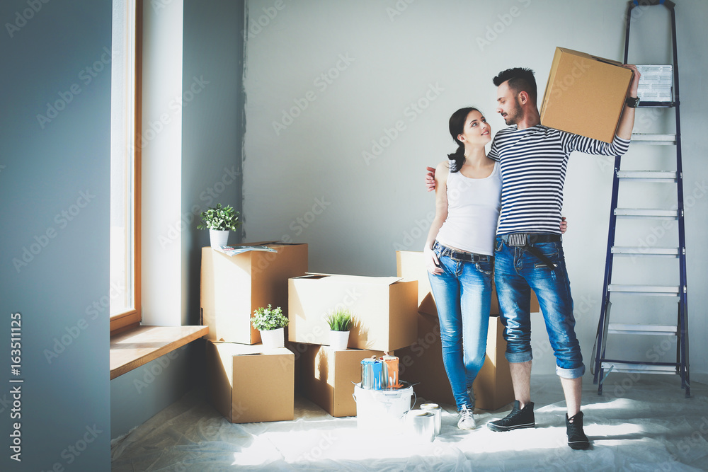 Happy young couple unpacking or packing boxes and moving into a new home - obrazy, fototapety, plakaty 