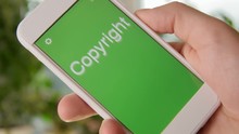 Copyrights Concept Application On The Smartphone. Man Uses Mobile App.