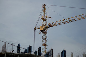 Crane and building construction.  New city place for many tall buildings under construction and cranes under a blue sky. Concrete building under construction. 